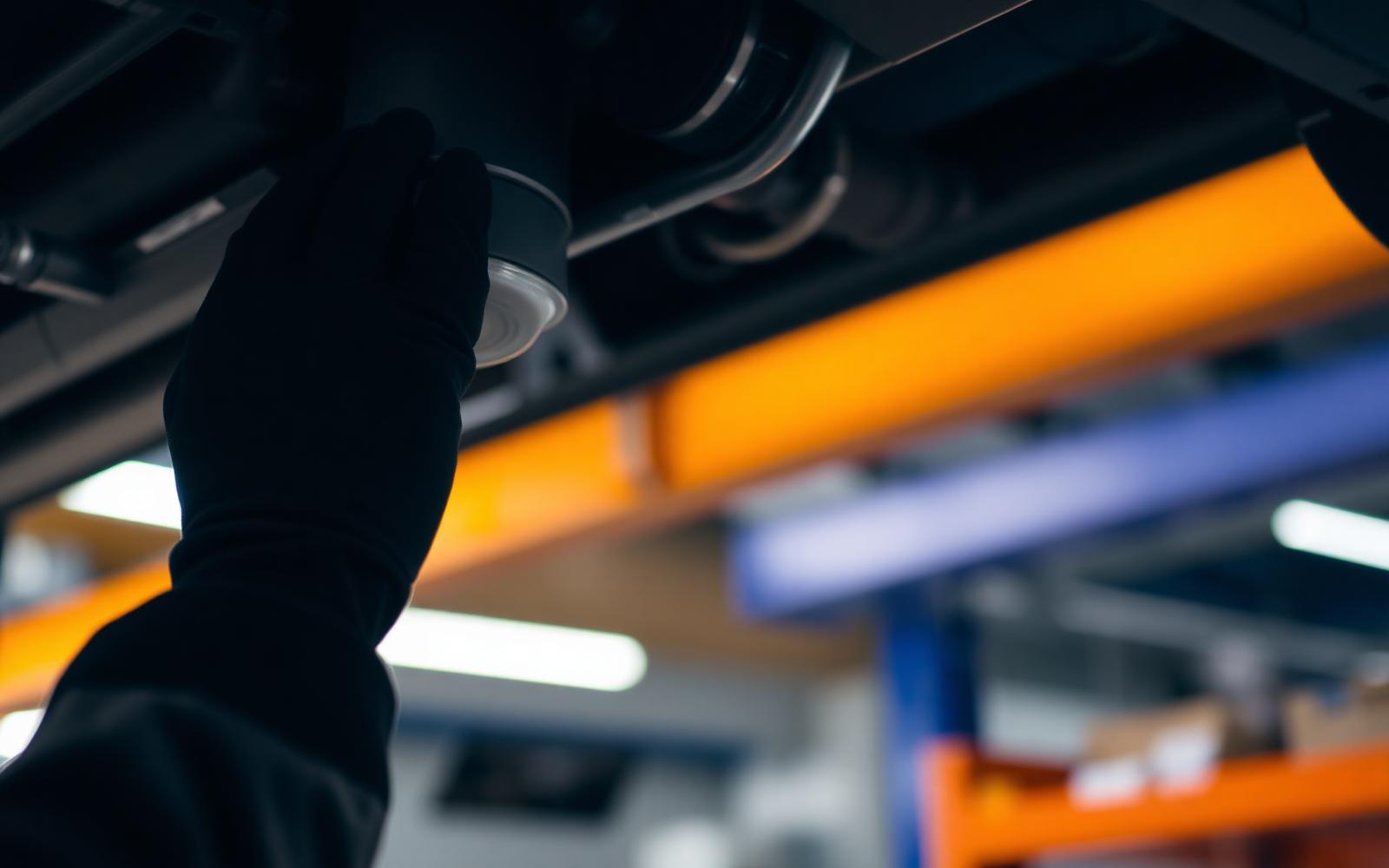 Mechanic performing an oil change under a lifted vehicle at Wilmington Oil, Lube and Filter